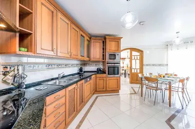a large kitchen with wooden cabinets and a table at Villa Encosta do Sol in Albufeira