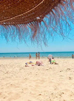 a group of people laying in the sand on the beach at Bougainvillea House in Faro