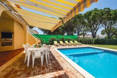 a patio with a table and chairs next to a pool at Villa Daffodil Golf in Vilamoura