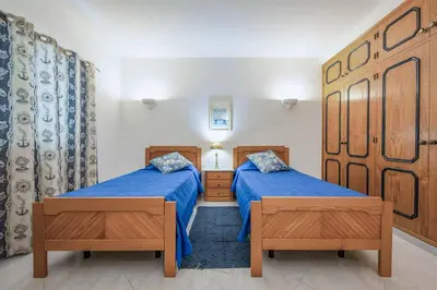 a bedroom with two beds with blue sheets and wooden furniture at Villa Mica in Azinhal