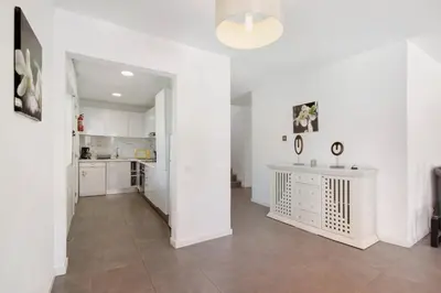 a white kitchen with white cabinets and a tile floor at Villa Lynn - Quadradinhos in Almancil