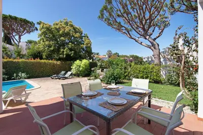 a patio with a table and chairs and a pool at Villa Lynn - Quadradinhos in Almancil