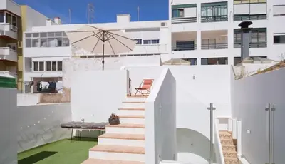 a white house with stairs and an umbrella at Casa Longa Faro - Traditional Portuguese House with modern comforts in Faro