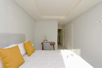 a bedroom with a bed with yellow pillows and a table at Birdie Bliss Apartment - CleverDetails - Sleeps 4 Adults and 1 Child in Vilamoura