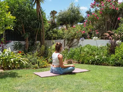 a woman sitting on the grass in a yoga pose at Beach villa Casa de Amanhã 450 mts to the beach with beautiful garden and heated saltwater pool in Albufeira