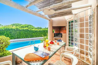 a patio with a table and chairs and a pool at Villa Silveira in Vilamoura