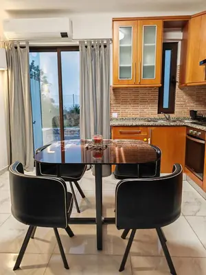 a kitchen with a glass table and four chairs at Apartamento Páteo - piscina, churrasqueira e vista jardim in Albufeira