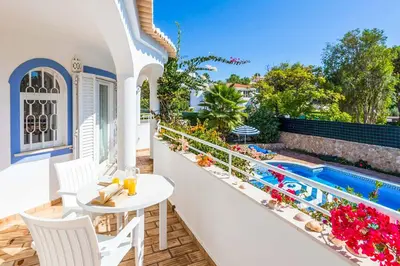 a balcony with a table and chairs next to a swimming pool at Villa Katharina in Albufeira