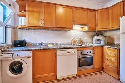 a kitchen with wooden cabinets and a washer and dryer at Casa Felix mit Pool in Albufeira