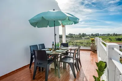 a table with chairs and an umbrella on a balcony at Casa Miranda in Albufeira