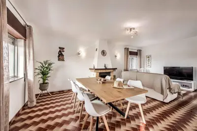 a living room with a wooden table and white chairs at Casa Miranda in Albufeira