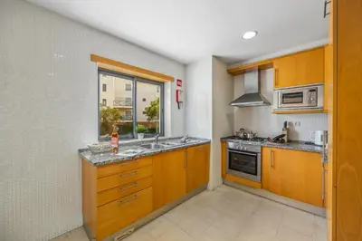 a kitchen with wooden cabinets and a sink and a window at Oleander Terrace Albufeira in Faro