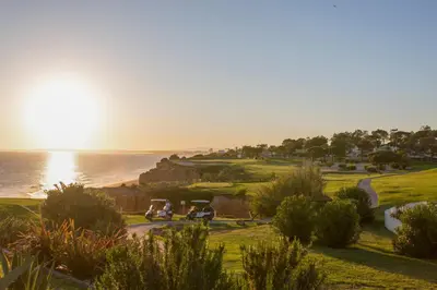 a golf course with two golf carts and the ocean at Oleander Terrace Albufeira in Faro