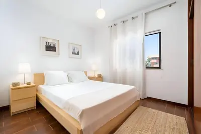 a white bedroom with a large bed and a window at Sal da Viana, Modern Ground Floor, Vilamoura in Vilamoura