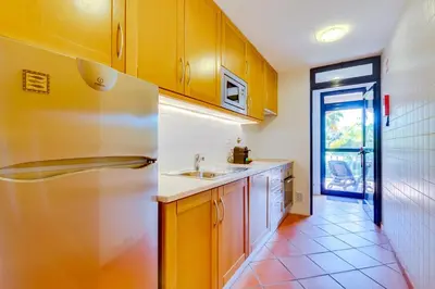 a kitchen with yellow cabinets and a stainless steel refrigerator at AL - Apartamento Vila Sol N in Vilamoura