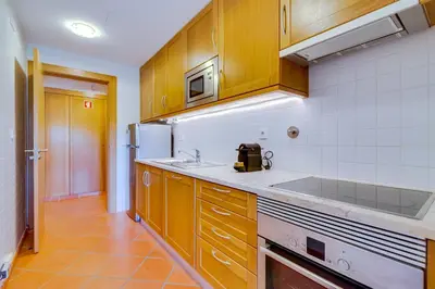 a kitchen with wooden cabinets and a sink and a refrigerator at AL - Apartamento Vila Sol N in Vilamoura