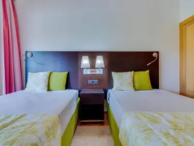 two beds in a hotel room with yellow and green pillows at AL - Apartamento Vila Sol Adaptado in Vilamoura