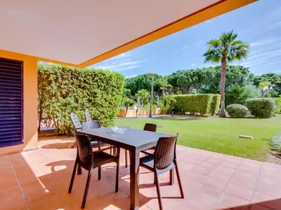 a table and chairs on a patio with a yard at AL - Apartamento Vila Sol Adaptado in Vilamoura