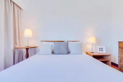 a bedroom with a large white bed with two lamps at AL - Moradia Vila Brasil in Vilamoura