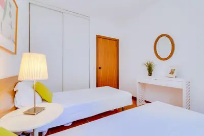 a room with two beds and a table with a lamp at AL - Moradia Vila Brasil in Vilamoura