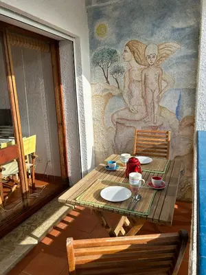 a wooden table with two chairs and a mural at Ouramar Apartment in Albufeira