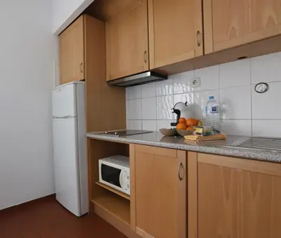 a kitchen with wooden cabinets and a white microwave at Apartamento Brisa Mar in Albufeira