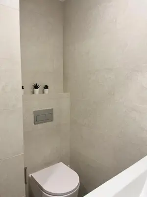 a bathroom with a toilet with two plants on a shelf at Montinho - Apartamento in Faro