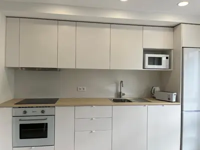 a kitchen with white cabinets and a sink and a microwave at Montinho - Apartamento in Faro