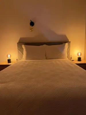 a large bed with white sheets and two lamps on tables at Romeu in Quarteira