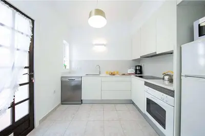 a white kitchen with a sink and a dishwasher at Casa do Engenho in Galé