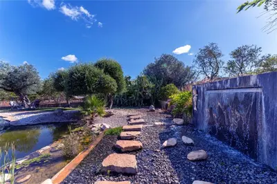 a garden with a stone path next to a pond at The Quinta Retreat Algarve Available to Facilitators yoga & sound therapies, massage mindfulness in Almancil