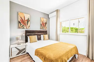 a white bedroom with a bed and two windows at Villa Corcovada in Albufeira