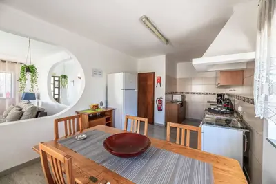 a kitchen and dining room with a wooden table and chairs at Villa Rosa dos Ventos in Galé