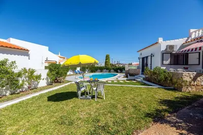 a garden with a table and chairs and a yellow umbrella at Villa Rosa dos Ventos in Galé