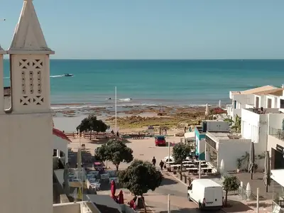a view of a town with a clock tower and the ocean at BEACH HOUSE in Olhos de Água