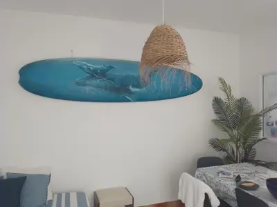 a pendant light in a living room with dolphins on the wall at BEACH HOUSE in Olhos de Água
