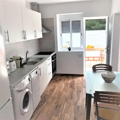a kitchen with white cabinets and a table with a sink at Casa Vitoria - Olhos de Agua - Albufeira in Roja- Pé