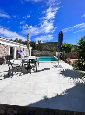a patio with a table and umbrella next to a pool at Typical quiet Algarve cottage in Faro