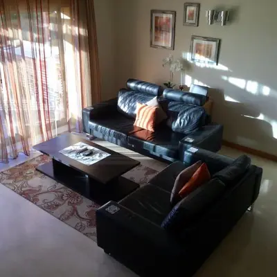 a living room with a black leather couch and a table at Apartment Rosmaninho-Hosted by Sweetstay in Quarteira