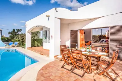 a dining area with a table and chairs next to a pool at Villa Gira in Albufeira