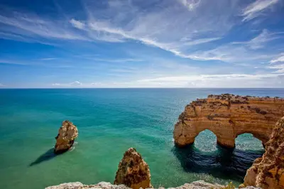 an arch in the ocean with rocks in the foreground at Meadow View Retreat in Albufeira