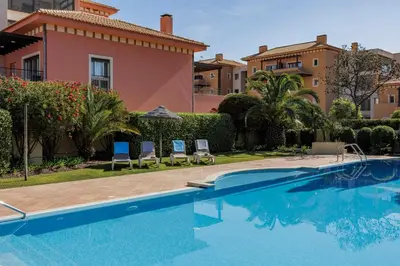 a swimming pool in front of a villa at Avenue Apartment Vilamoura in Quarteira