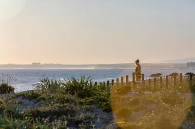 a man sitting on a fence looking at the ocean at Avenue Apartment Vilamoura in Quarteira