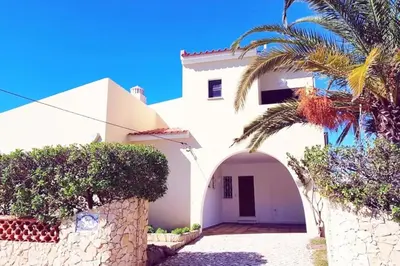 a white house with a palm tree in front of it at Villa Mirasol - Relaxed Private Villa in Albufeira