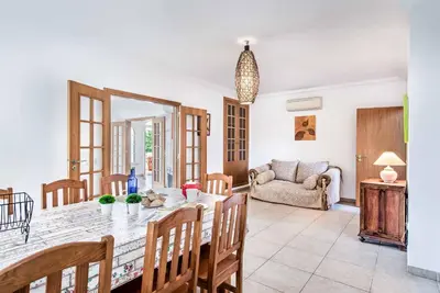 a dining room and living room with a table and chairs at Villa Godinho in Albufeira