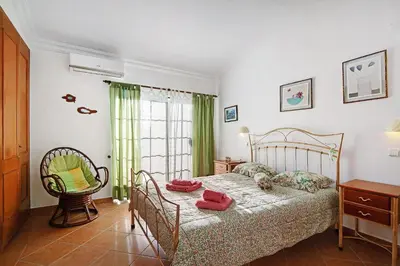 a bedroom with a bed and a chair and a window at Casa Estrela do Mar, 2 Quartos, Praia de São Rafael, Albufeira in Albufeira