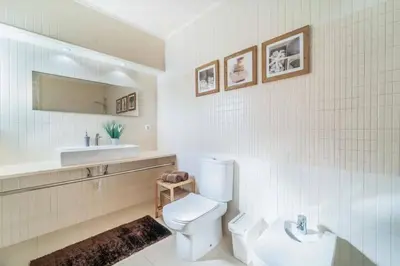 a white bathroom with a toilet and a sink at Villa Catarino in Albufeira