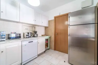 a kitchen with white cabinets and a stainless steel refrigerator at Villa Catarino in Albufeira