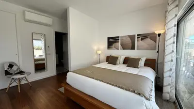 a white bedroom with a large bed and a chair at Harmony by Check-in Portugal in Albufeira