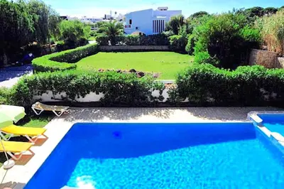 a blue swimming pool in a yard with a house at Villa Palmeiras - Serene Private Villa in Albufeira